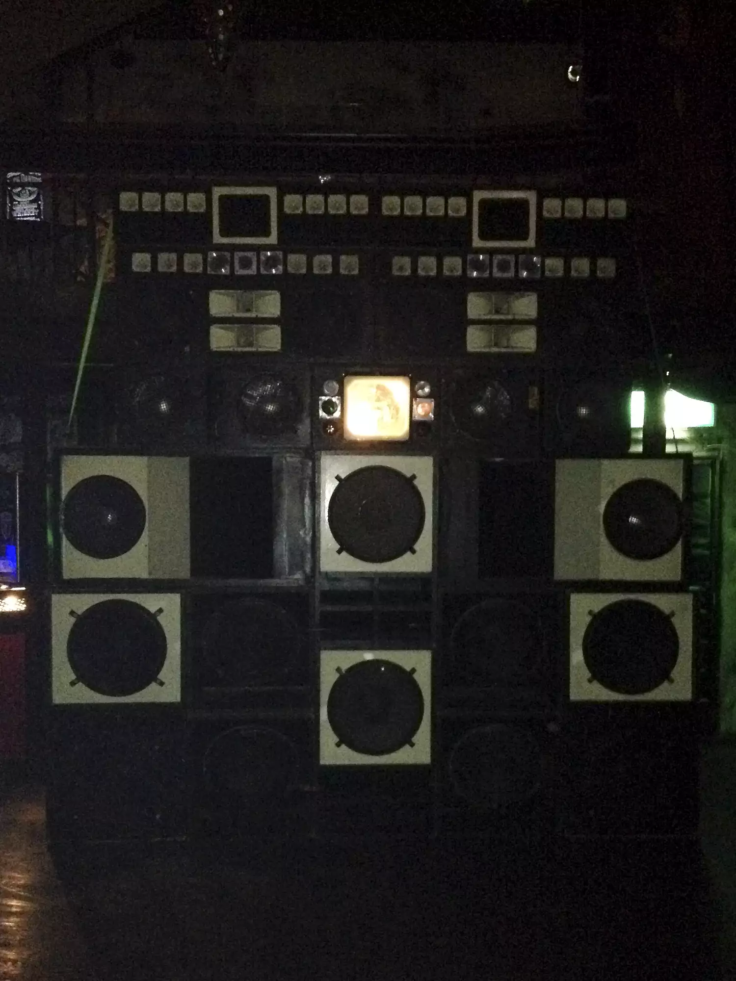 A picture of a huge sound system.Black and whit speaker boxes built up way higher than human. Inthe center there is a mirror ball inside the Speaker.